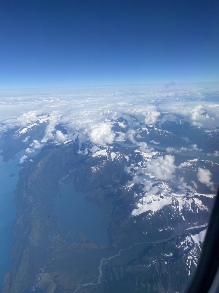 View of snow covered mountians out of airplane window.