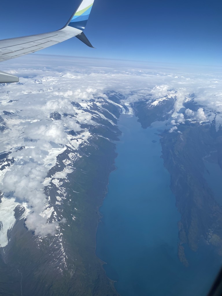 View of snow covered mountians out of airplane window.