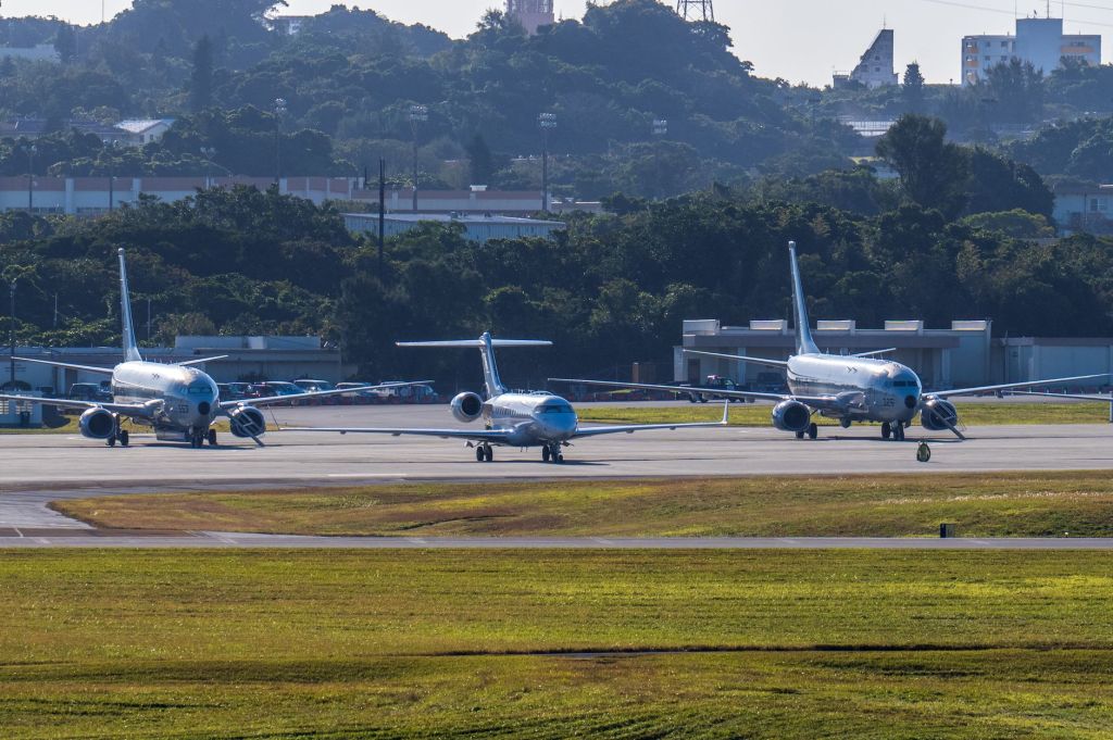 Three commercial airplanes sitting side by side on tarmac.
